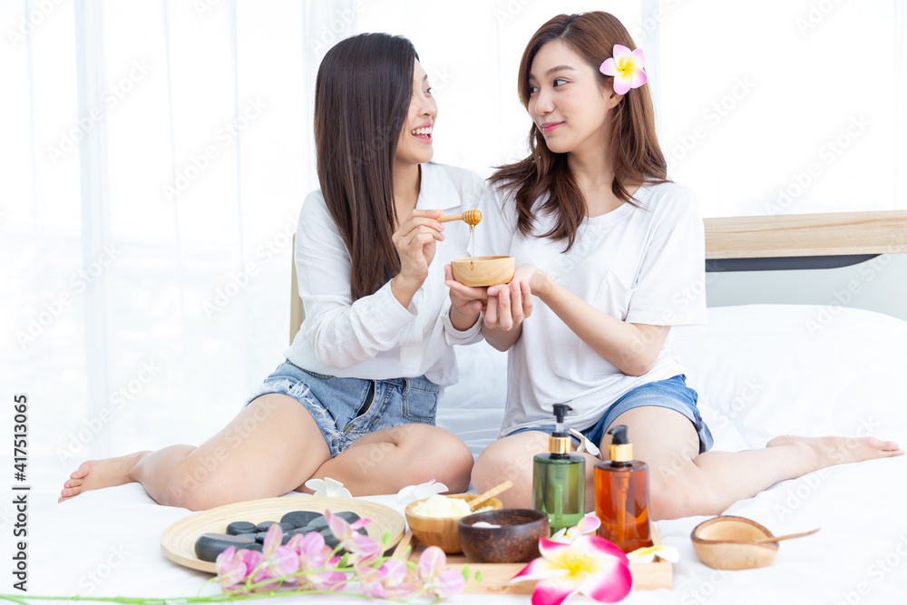 Two young Asian women are enjoying the preparation of spa equipment. Smiling long hair young girl with friends doing DIY spa by herself at home in white bedroom. Two young Asian women are enjoying the preparation of spa equipment. Smiling long hair young girl with friends doing DIY spa by herself at home in white bedroom.
