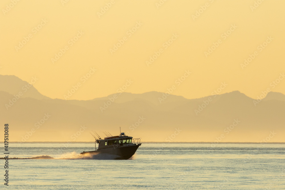 USA, Alaska, Petersburg, Sport fishing boat motors across calm water of Frederick Sound on summer evening.