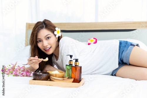 Young Asian women are enjoying the preparation of spa equipment. Smiling young girl waiting for a DIY home spa treatment in her white bedroom.