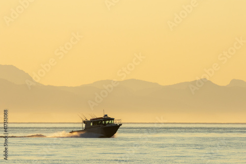 Photography USA, Alaska, Petersburg, Sport fishing boat motors across calm water of Frederick Sound on summer evening