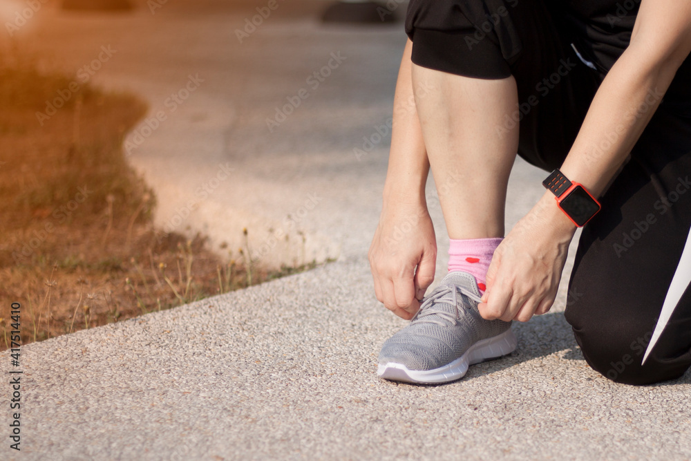 A woman runner tying shoelaces before workout at the park.