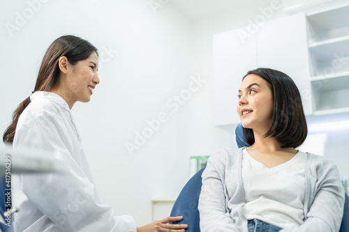 Caucasian girl consulting Asian female dentist about oral care checkup