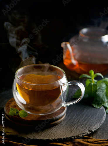 Tea concept, teapot with tea surrounded on wood background, tea ceremony, green tea in a transparent cup