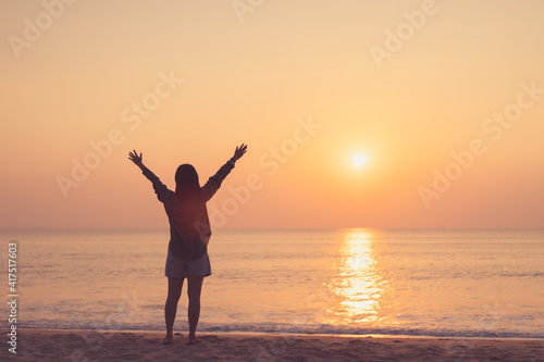 Copy space of woman rise hand up on sunset sky at beach and island background.