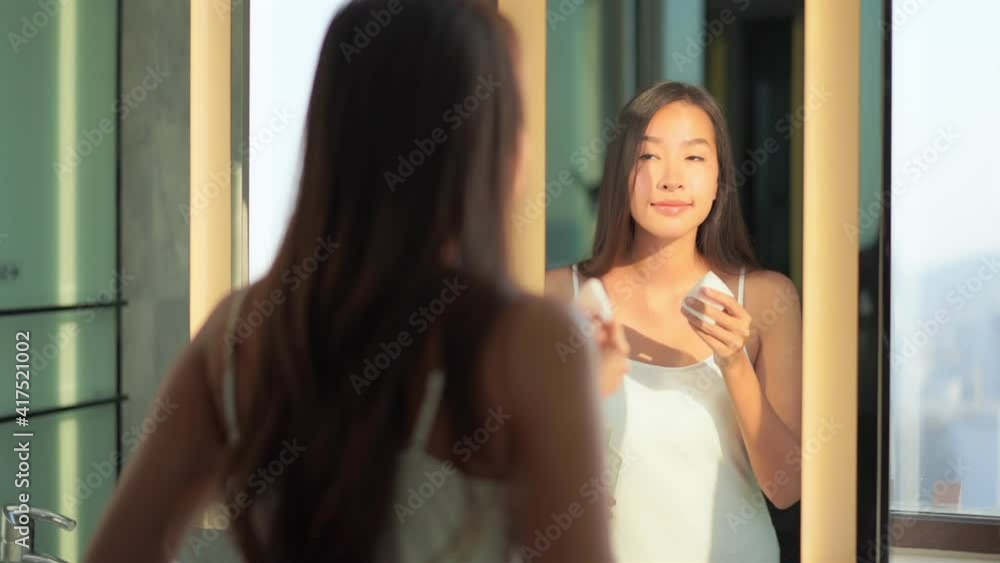 Young Asian girl with cleanser bottle and cotton pad remove cosmetic from face Young Asian girl with cleanser bottle and cotton pad remove cosmetic from face