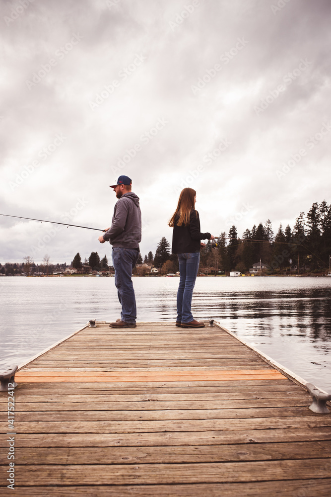 father and daughter fishing on dock 