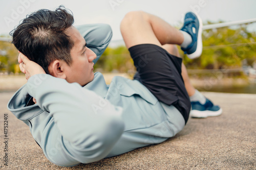 Young sportsman doing cyling crunches in park. photo