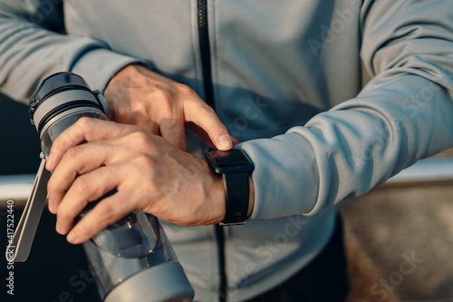 sport man checking at smartwatch during training and running in the park.