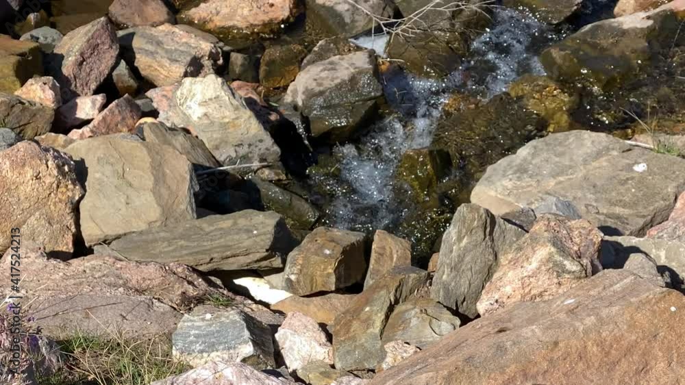 Water flowing amid rocks in tiny mountain stream on sunny day Water flowing amid rocks in tiny mountain stream on sunny day