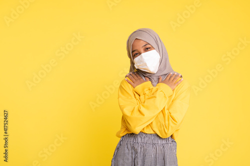 Woman wearing face mask during coronavirus outbreak isolated on yellow background.