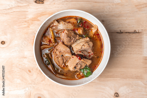 Spicy soup with pork ribs on wood table. photo