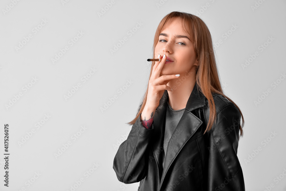 Young smoking woman on grey background Young smoking woman on grey background