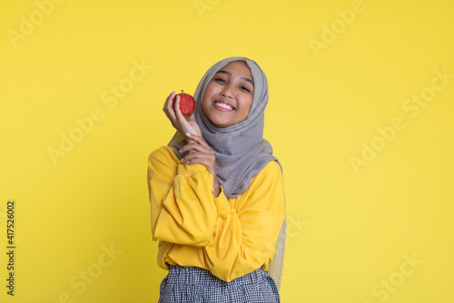 beautiful girl with red apple on yellow background © faishalabdula