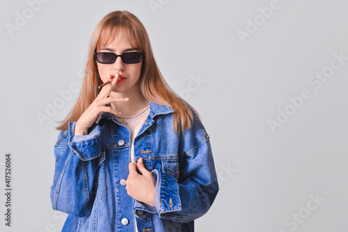 Young smoking woman on grey...