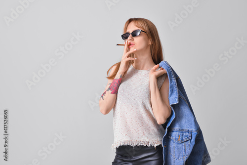 Young smoking woman on grey...
