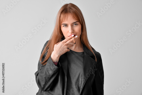 Young smoking woman on grey...