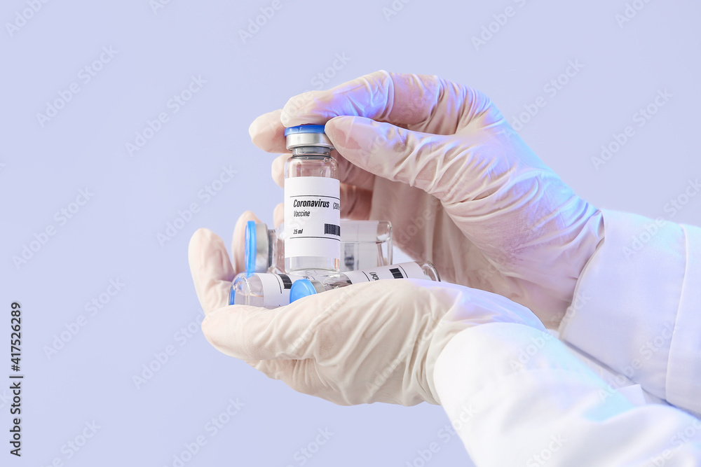 Doctor's hands with vaccine against COVID-19 on color background Doctor's hands with vaccine against COVID-19 on color background