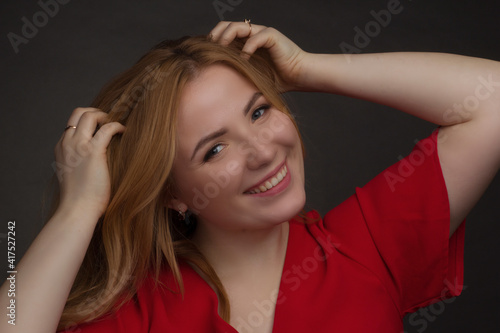 a blonde girl with an overweight plus size, a red overallposing on a dark Studio background