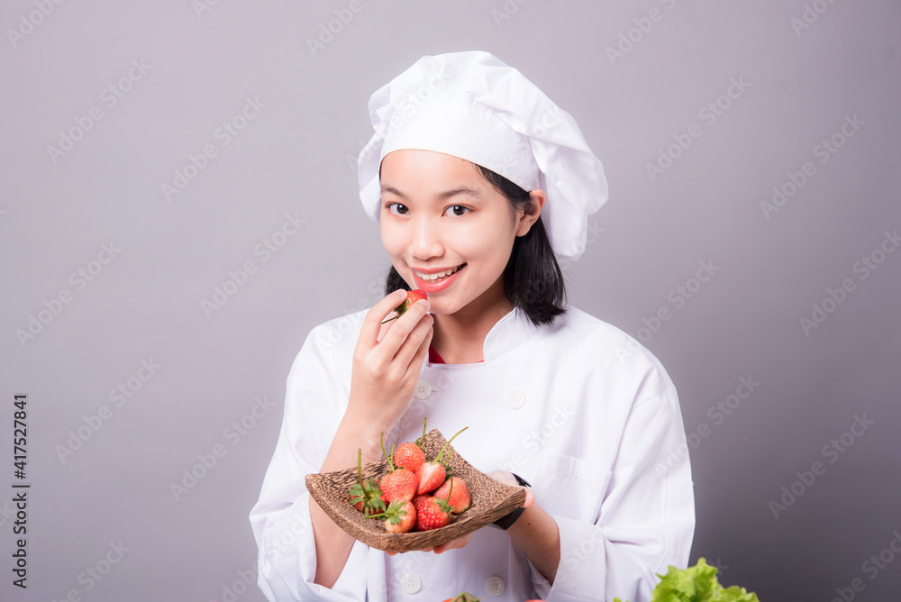 Portrait of a young Asian female chef ready to cook a new dish in the kitchen. Contains Strawberry as an ingredient Portrait of a young Asian female chef ready to cook a new dish in the kitchen. Contains Strawberry as an ingredient