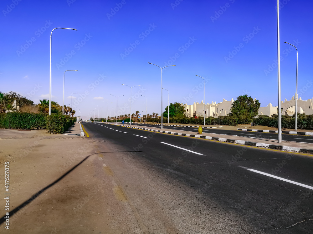 Empty city street with large jugs on the sidewalk in Sharm El Sheikh (Egypt). Cityscape of tropical egyptian town with deserted road