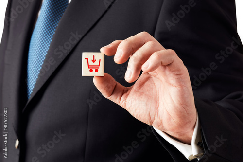 Businessman shows a wooden cube with shopping cart icon. Online shopping or add to basket