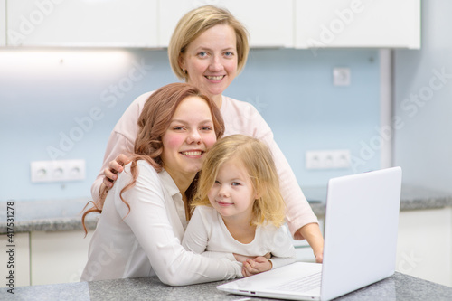 Mom and daughter and granddaughter are sitting at the kitchen table and looking at the camera