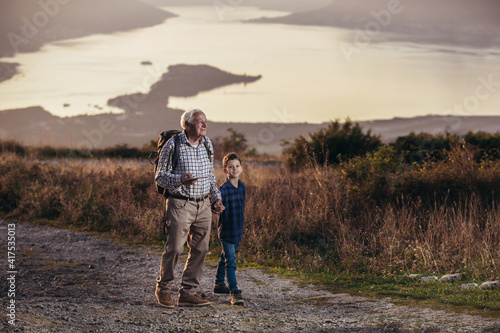 Grandfather and grandson hiking, using digital tablet.