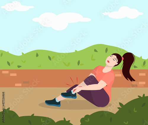 a young brunette woman sits on the ground in a park and holds on to a sore leg injured while running. The concept of a healthy lifestyle and injuries during sports © NataSao