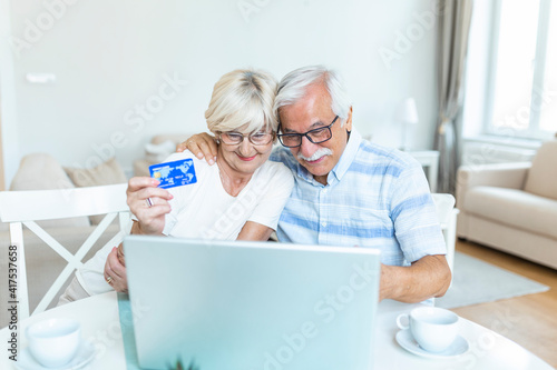 Senior Couple Using Laptop To Shop Online. Elderly couple paying bills online on laptop. Excited senior woman showing smiling middle aged husband online shopping sale on web site
