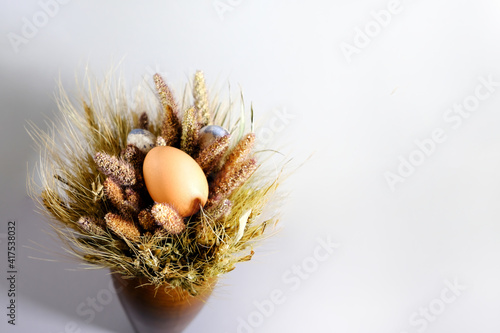 Easter egg in a nest of dried flowers. On a gray background. Top view of the purchase plan. Background for congratulations or your design.
