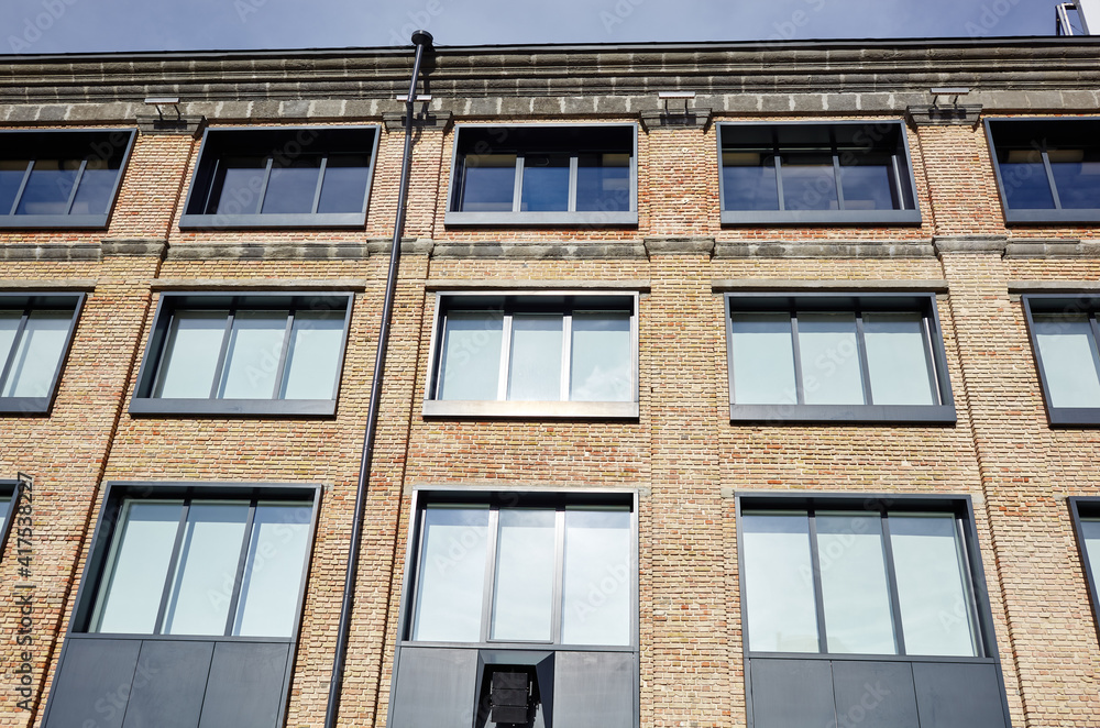 Fototapeta premium Brick building with windows and downspout against blue sky