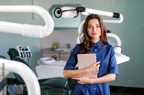 Young doctor in a dental clinic. Portrait of young female doctor dentist with digital tablet in dental office photo