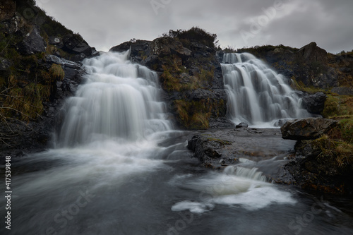 double waterfall in river with silky water. dry autumn grass- Fairy Pools - Skye Island - Scotland - Uk