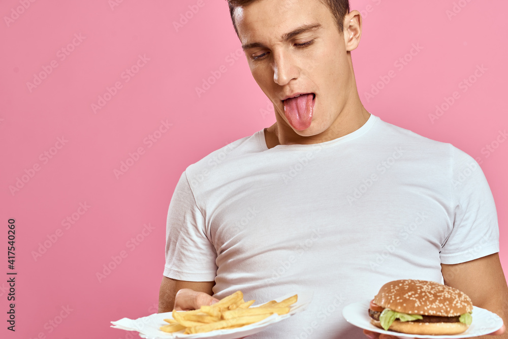 man in white t-shirt hamburger lifestyle pink background eating