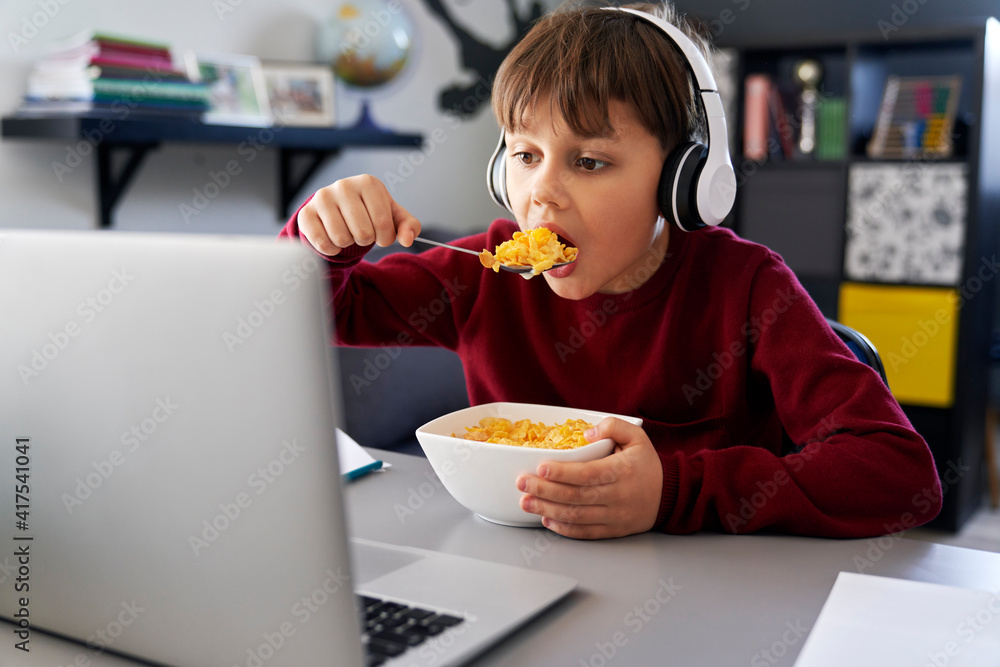 Boy eating breakfast during online classes Boy eating breakfast during online classes
