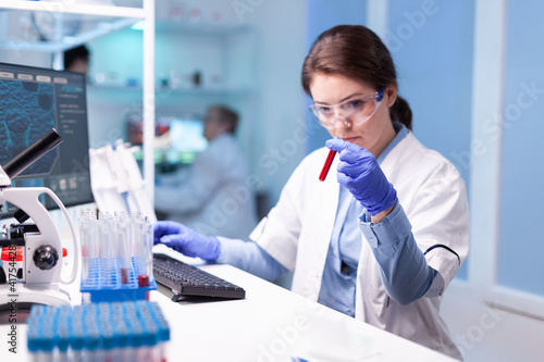 Biotechnologist woman scientist researching with a blood tube in pharma lab. Modern laboratory for scientific research with professional equipment for virus study and healtcare photo