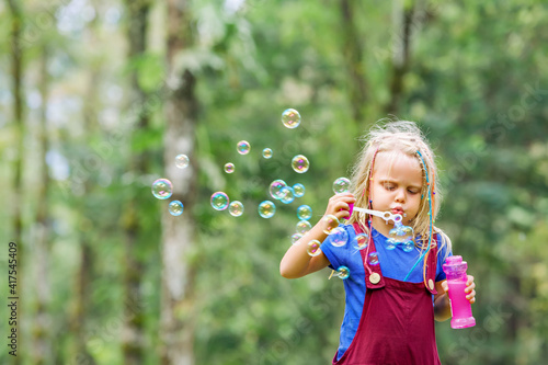 Happy girl playing with soap bubbles. Active child walking in the park. Family lifestyle  outdood activities  summer holidays with kids. 