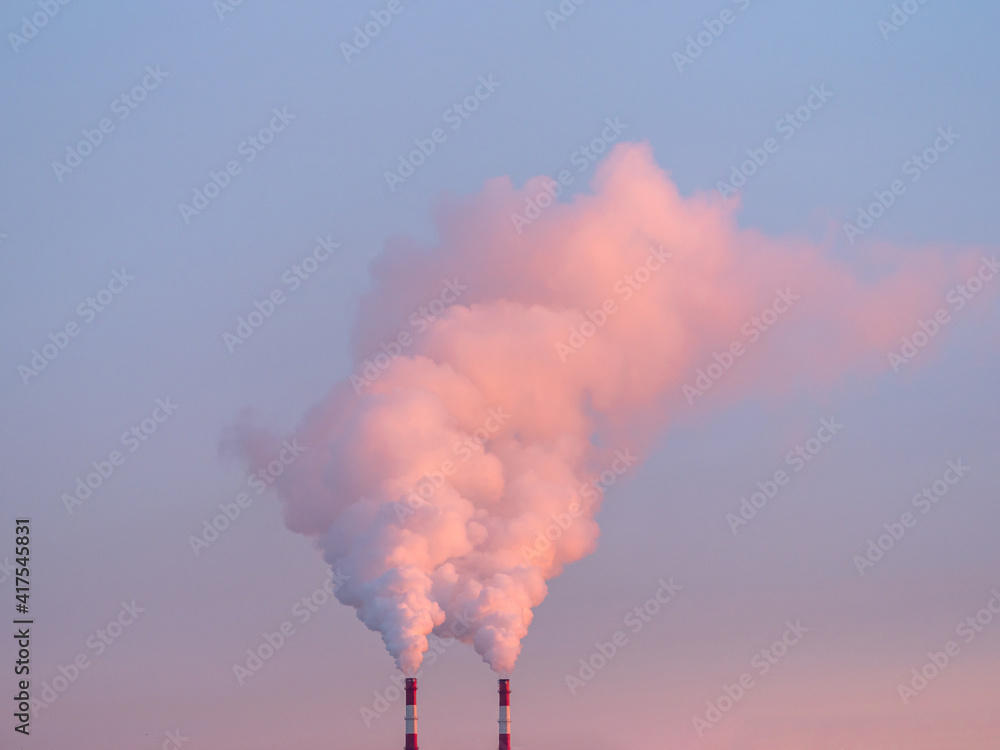 Smoke from chimneys of heating plant. Air pollution. Factory pipes with smoke, frosty weather, sunrise. Ecology problem.