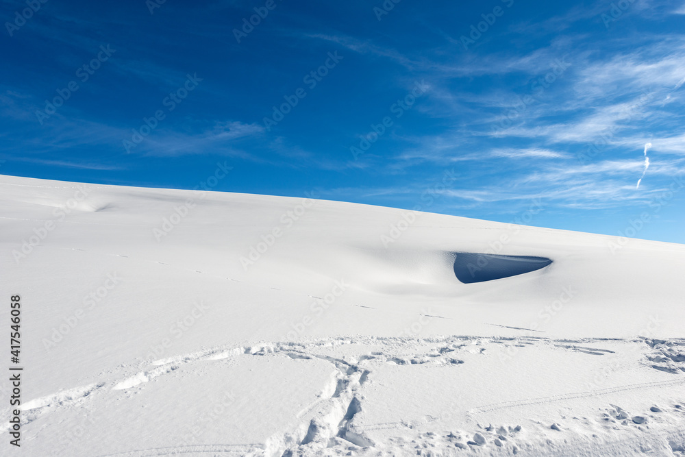 Closeup of a winter landscape with powder snow on blue sky with clouds. Lessinia Plateau (Altopiano della Lessinia), Regional Natural Park, Verona Province, Veneto, Italy, Europe.