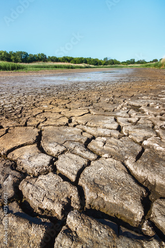 Cracked soil on riverbank of dried waterless river in summer drought