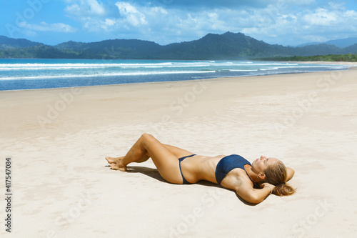 Happy young woman relax on tropical sand beach. Red island beach, pantai Pulau merah, Banyuwangi, east Java, Indonesia. Popular travel destination in Asia. Summer vacation lifestyle photo