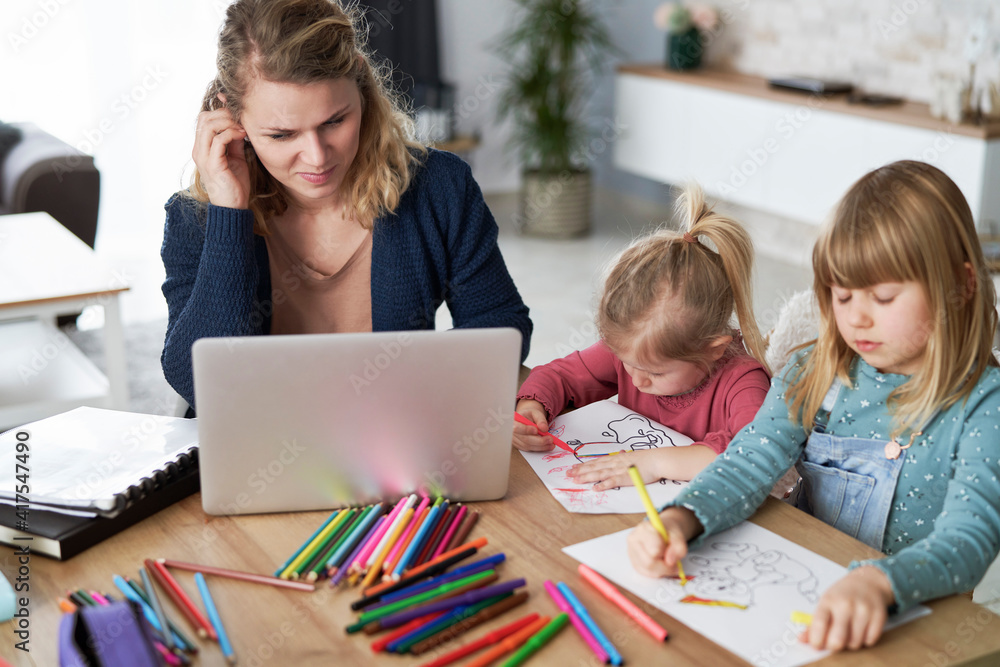 Mother working at home and looks after her daughters Mother working at home and looks after her daughters