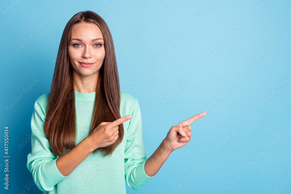 Photo portrait of calm woman pointing two fingers at blank space isolated on pastel blue colored background Photo portrait of calm woman pointing two fingers at blank space isolated on pastel blue colored background