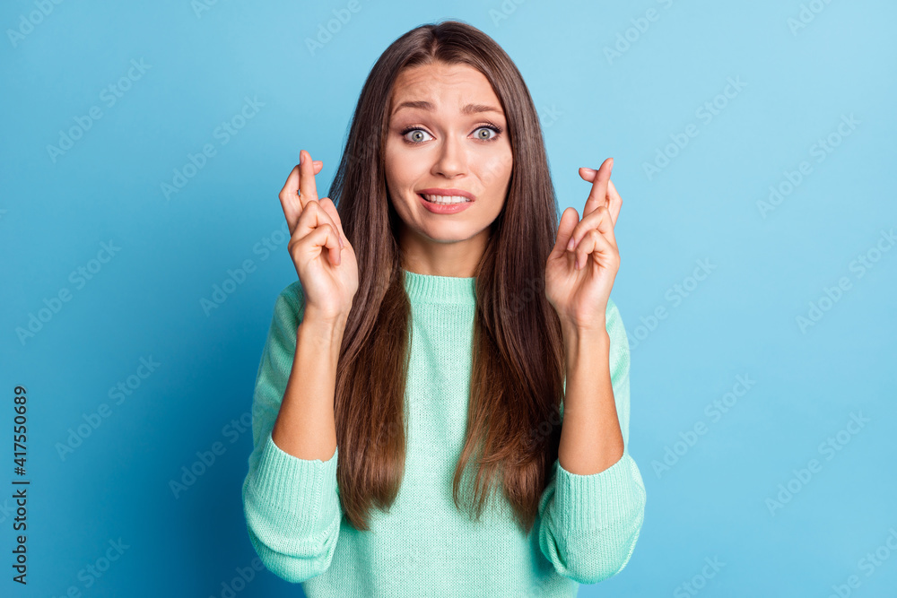 Portrait of charming confused brown-haired girl crossed fingers expecting news isolated over bright blue color background Portrait of charming confused brown-haired girl crossed fingers expecting news isolated over bright blue color background