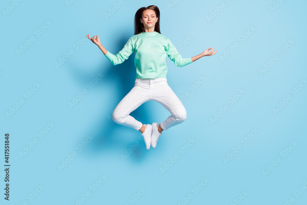 Full length body size view of lovely calm focused girl jumping sitting lotus pose meditating isolated on bright blue color background