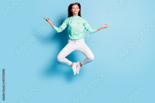 Full length body size view of lovely calm focused girl jumping sitting lotus pose meditating isolated on bright blue color background