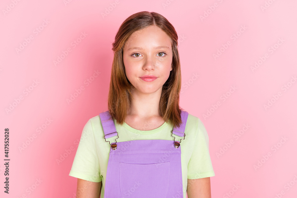 Photo portrait of small girl wearing purple overall isolated on pastel pink color background Photo portrait of small girl wearing purple overall isolated on pastel pink color background