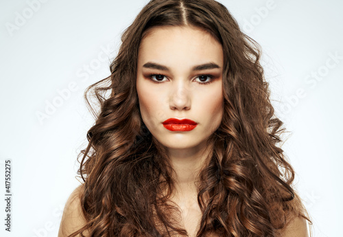 Woman with curly hair grooming naked shoulders and bright makeup