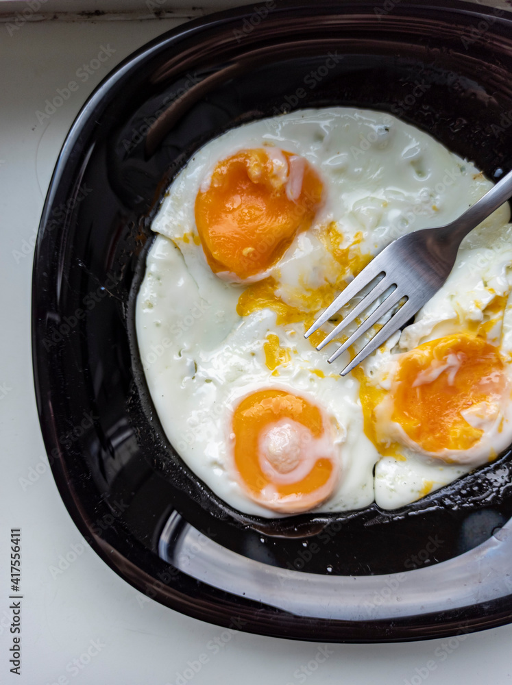photo of fried eggs in a black plate on a white background. food photo