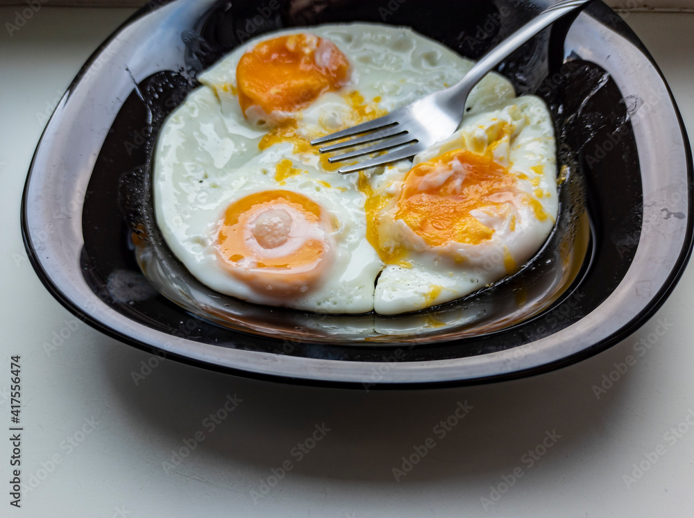photo of fried eggs in a black plate on a white background. food photo